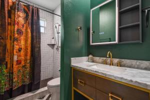 Un baño verde con lavabo y espejo. en Pool Table, BBQ, Walking Distance to Local Gems, en Orlando