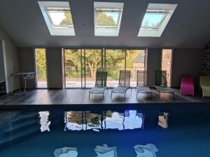 a room with a pool with chairs and windows at le petit moulin de Kerloroc in Ploudalmézeau