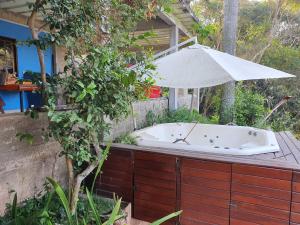 a bath tub with an umbrella on a deck at Chácara c piscina in Cotia