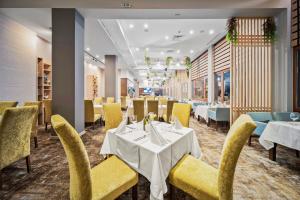 a restaurant with white tables and yellow chairs at Hotel Orlovetz in Pamporovo +51 photos