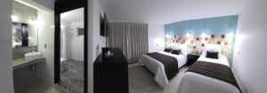 a hotel room with two beds and a bathroom at Condesa Hotel Boutique Zacatlán in Zacatlán