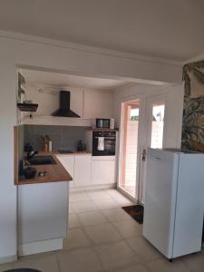 eine Küche mit weißen Schränken und einem weißen Kühlschrank in der Unterkunft La Canopée - Appartement F2 avec piscine - vue mer in Le Robert