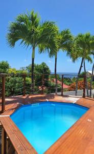 einen Pool mit Palmen auf einer Terrasse in der Unterkunft La Canopée - Appartement F2 avec piscine - vue mer in Le Robert
