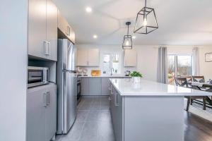 a white kitchen with a refrigerator and a table at City Oasis with Free Parking and Stylish Urban Gem in Longueuil