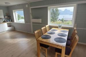 ein Esszimmer mit Tisch und Stühlen und zwei Fenstern in der Unterkunft Segla view house in Mefjordvær