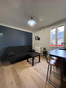 a living room with a black couch and a table at Résidence des Carmes in Dol-de-Bretagne