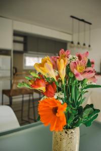 a vase filled with colorful flowers on a table at Conana Apartment in Villa Mercedes