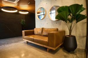 a brown leather couch and a potted plant in a room at HYPE STATES Cali in Cali