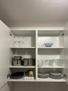 a white cabinet with plates and dishes in it at Schöne Wohnung für Tagesgäste, Studenten oder Handwerker, Chemnitz Gablenz, ÖPNV direkt vor der Tür, Internet & TV inkl in Chemnitz