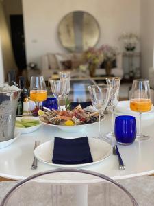 a white table with a plate of food and wine glasses at Attico Reale - in Centro, tra Stazione e Bari Vecchia in Bari