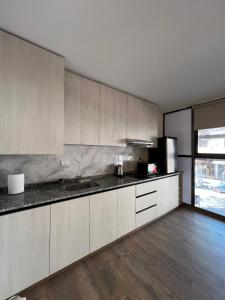 une cuisine avec des armoires blanches et un plancher en bois dans l'établissement Departamento Carlos Paz, à Villa Carlos Paz