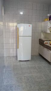 a kitchen with a white refrigerator in a room at Cantinho da Lu em Santa Mônica in Guarapari