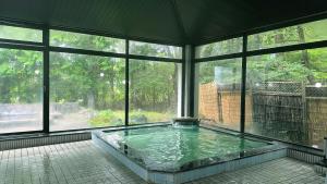 Habitación con bañera de hidromasaje y ventanas grandes. en Hotel Kosho, en Nikko