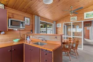 a kitchen with a sink and a dining room with a table at Waterfront Charm - Snells Beach Holiday Home in Snells Beach