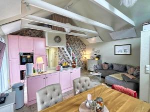 ein Wohnzimmer mit rosa Schränken und einem Tisch in der Unterkunft Ferienhaus Büdnerstube gratis Schwimmbadnutzung im AHOI Sellin in Middelhagen