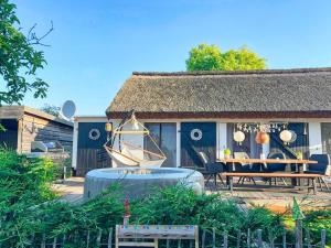 ein Haus mit einer Terrasse mit einem Tisch und einem Boot in der Unterkunft Ferienhaus Büdnerstube gratis Schwimmbadnutzung im AHOI Sellin in Middelhagen
