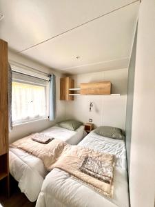 2 łóżka w małej sypialni z oknem w obiekcie Un toit sur le bassin bungalow w mieście Claouey +11 zdjęć