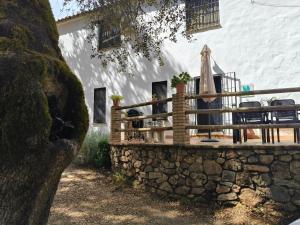 a house with a stone wall and a wooden deck at Casa rural Alicia in Cortegana