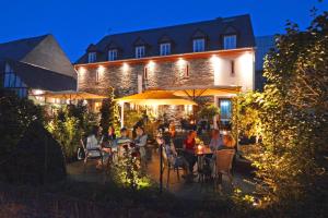 un groupe de personnes assises à des tables devant un bâtiment dans l'établissement Juffer Flair Restaurant Gästehaus, à Brauneberg