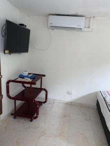 Una habitación con una mesa y un televisor en una pared. en CASA HOTEL TOSCANINI (T), en Cali