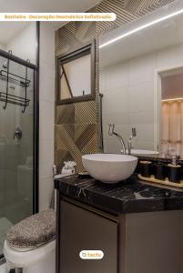 une salle de bain avec un lavabo, des toilettes et un miroir dans l'établissement Appartement Moderne au VG Sun Cumbuco par Tactu, à Paracumbuca