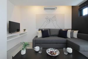 een woonkamer met een bank en een tv bij b hotel Heiwaodori 201 - New Apt in Famous Hiroshima Dori Max 6p in Hiroshima