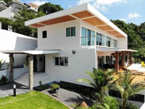 una casa blanca con una palmera delante en SunTien a spectacular 4br beach front pool villa, en Ko Pha Ngan