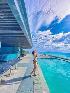 une femme en bikini marchant à côté d'une piscine dans l'établissement GRAND HYCHARMS serviced STUDIO, à Quy Nhơn