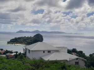 a white house on a hill next to a body of water at Windsor Apartment in Kingstown +7 photos