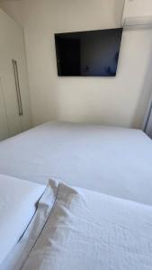 a bedroom with a bed with a tv on the wall at 2qts, 2 AR, 3 TV, Perto da Praia, Garagem in Itaparica