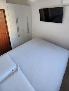 a room with a bed and a tv on a wall at 2qts, 2 AR, 3 TV, Perto da Praia, Garagem in Itaparica