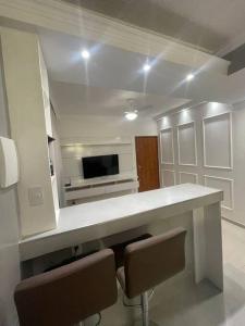 a white kitchen with a counter with two chairs at 2qts, 2 AR, 3 TV, Perto da Praia, Garagem in Itaparica