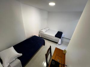 Habitación pequeña con 2 camas y mesa de madera. en Flat completo para até 4 pessoas no Vidigal - RJ, en Río de Janeiro