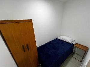 Un pequeño dormitorio con una cama azul y una puerta de madera en Flat completo para até 4 pessoas no Vidigal - RJ, en Río de Janeiro 16 fotos más