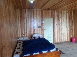 a bedroom with a bed in a wooden wall at Adithyanaman Cottage Homestay in Darjeeling