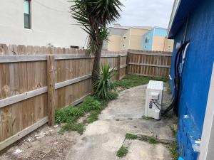 a fence with a bench next to a palm tree at Be A Nomad - Beach Cottage Oceanfront in Jacksonville Beach