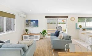a living room with two blue couches and a kitchen at Azul Blue at Shellys in Port Macquarie