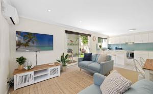 a living room with a blue couch and a kitchen at Azul Blue at Shellys in Port Macquarie