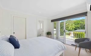 a white bedroom with a bed and a balcony at Azul Blue at Shellys in Port Macquarie