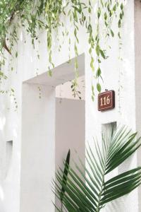 ein Schild an der Seite eines weißen Gebäudes mit Pflanzen in der Unterkunft Lubdhaka Canggu in Canggu