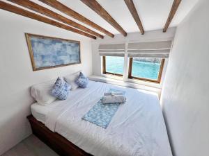 een slaapkamer met een bed met blauwe kussens en een raam bij Leticia Liveaboard in Labuan Bajo