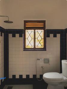 Un baño con inodoro y ventana. en Blue Swan Inn, en Unawatuna