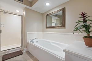 ein weißes Bad mit einer Badewanne und einem Spiegel in der Unterkunft Fun 2 bed/2 bath condo with pool on Biloxi Beach in Biloxi + 30 Fotos