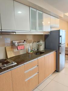 a kitchen with white cabinets and a stainless steel refrigerator at Cozy 1BR Condo with Uptown Mall View - BGC Zen Suite in Manila