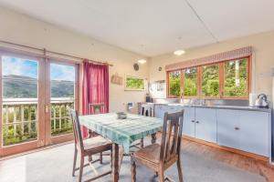 a kitchen with a table and chairs and a kitchen withwindows at Pukeko Cottage - Marlborough Sounds Retreat in Linkwater