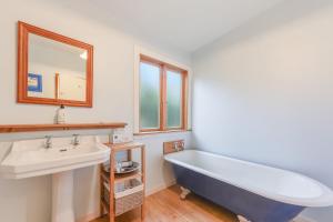 a bathroom with a blue tub and a sink at Pukeko Cottage - Marlborough Sounds Retreat in Linkwater +17 photos