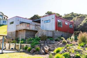 a home with a red and white house at Whero Pods - Mangawhai Heads Holiday Home in Mangawhai