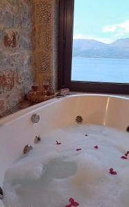 wanna wypełniona wodą obok okna w obiekcie Luxury suite of Villa Lagkadaki w mieście Agriliá