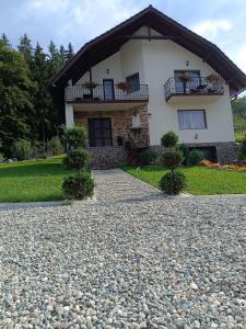ein Haus mit einem Balkon und einer Kieseinfahrt in der Unterkunft Casa Magnolia in Poiana Mărului