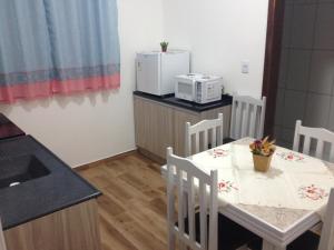 a kitchen with a table and chairs and a microwave at Pousada Suite Master Bella Mar in Penha